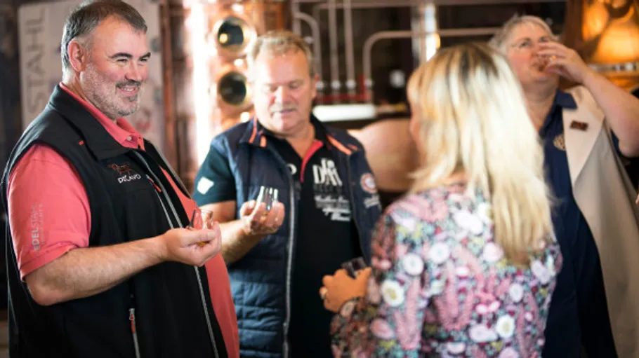 Group of people tasting drinks in a distillery.