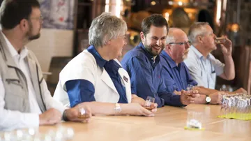 Group tasting drinks at a wooden table.