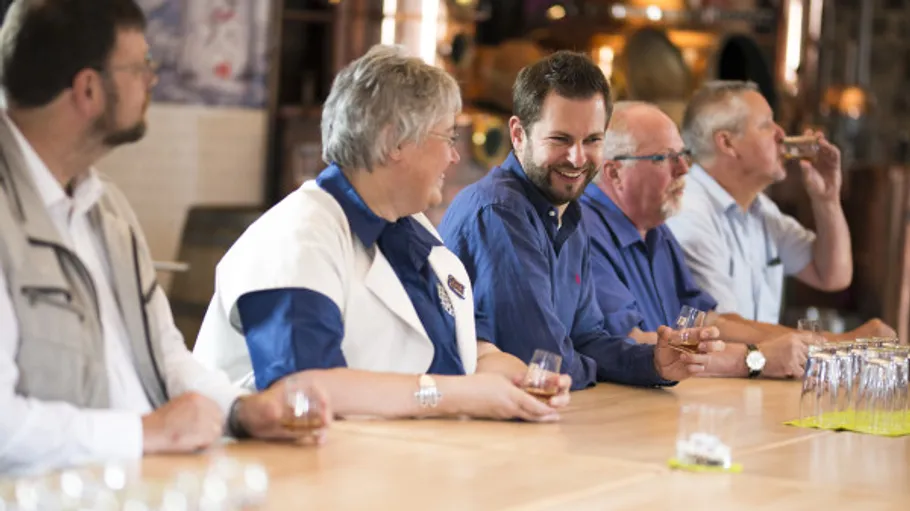 Group tasting drinks at a wooden table.