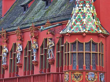Red building with decorated windows and figures.