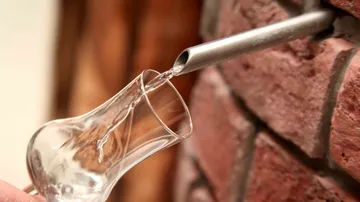 Glas wird mit Flüssigkeit aus Zapfhahn gefüllt.