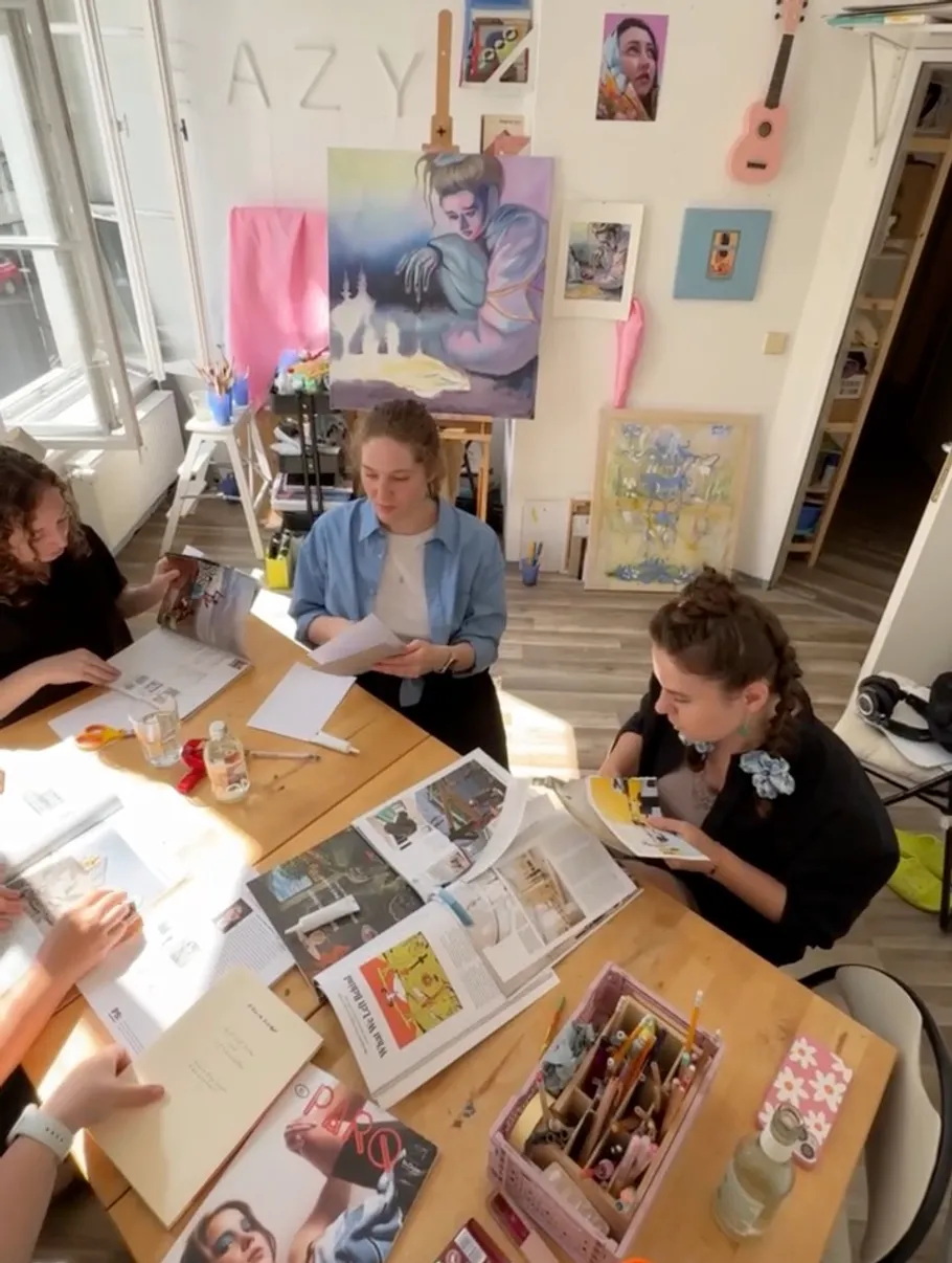 People crafting at table in bright art studio.