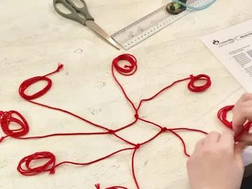 Red strings are connected together at a table.