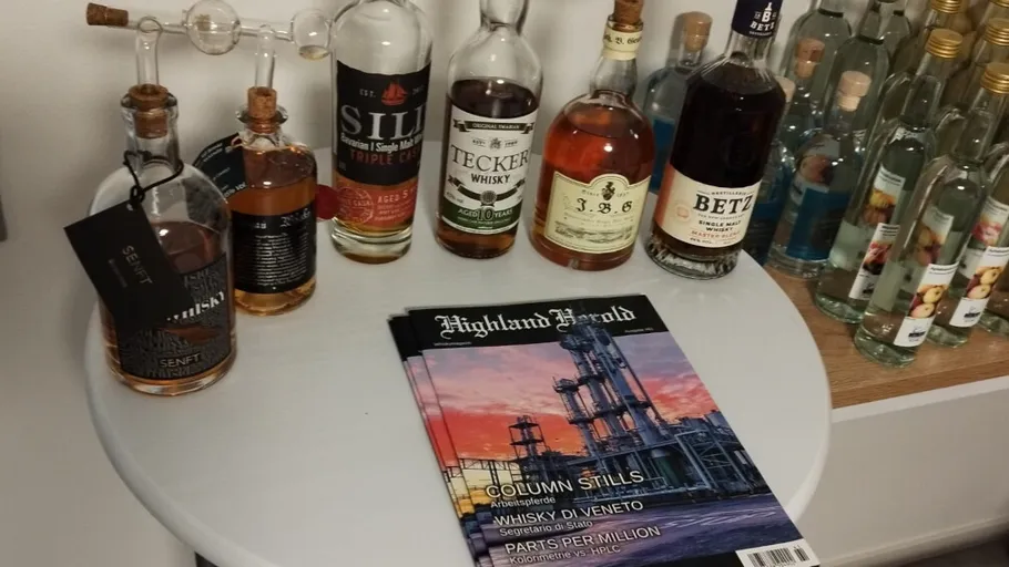 Various whiskey bottles and a magazine on table.