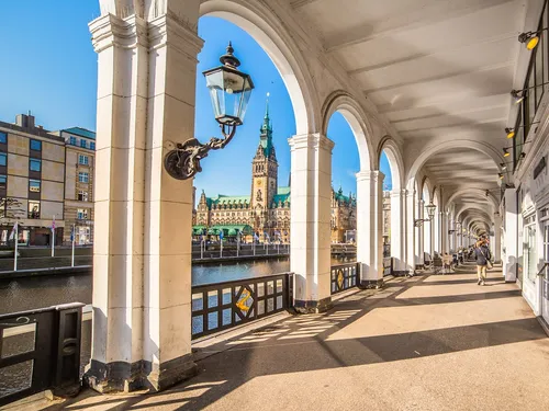 Arc-shaped pillars frame a path along a stream of water.