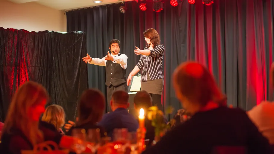 Two performers on stage with audience watching.