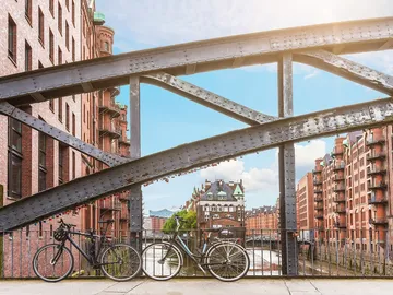 Two bikes lean against a bridge, the surrounding area is urban.