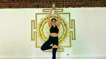 Woman balances in yoga pose holding trophy indoors.