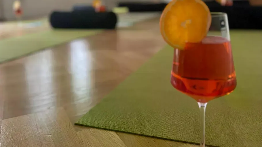 Glass of Aperol spritz on yoga mat.