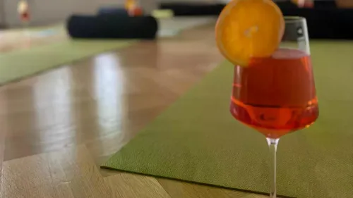 Glas mit Getränk und Orange auf Yogamatte.