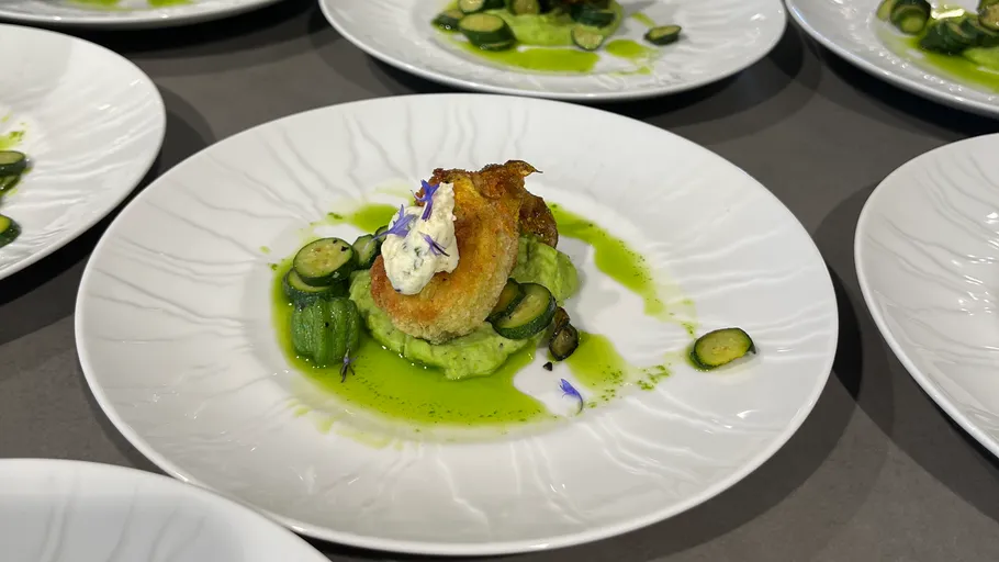 Gourmetgericht auf weißem Teller, grüne Soße.