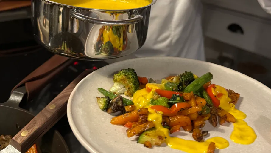 Vegetables on plate with yellow sauce poured.