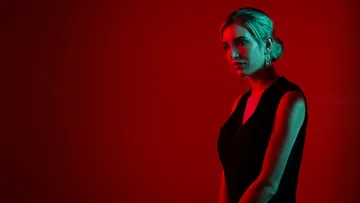 Woman standing against a red background.