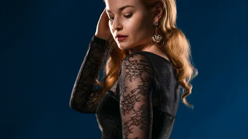 Frau im Spitzenkleid blickt nach unten, blauer Hintergrund.