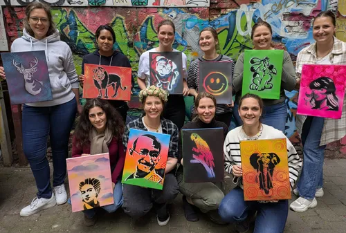 Group holding stencil art paintings, graffiti background.