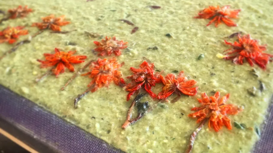Orange flowers embedded in green handmade paper.