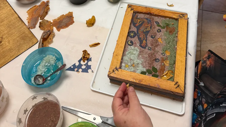 Hand crafting decorative paper frame indoors.