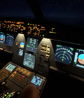 Airplane cockpit with illuminated controls, nighttime.