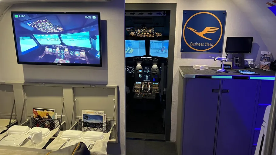 Flugzeug-Cockpit-Simulator neben Business-Class-Sitzen.