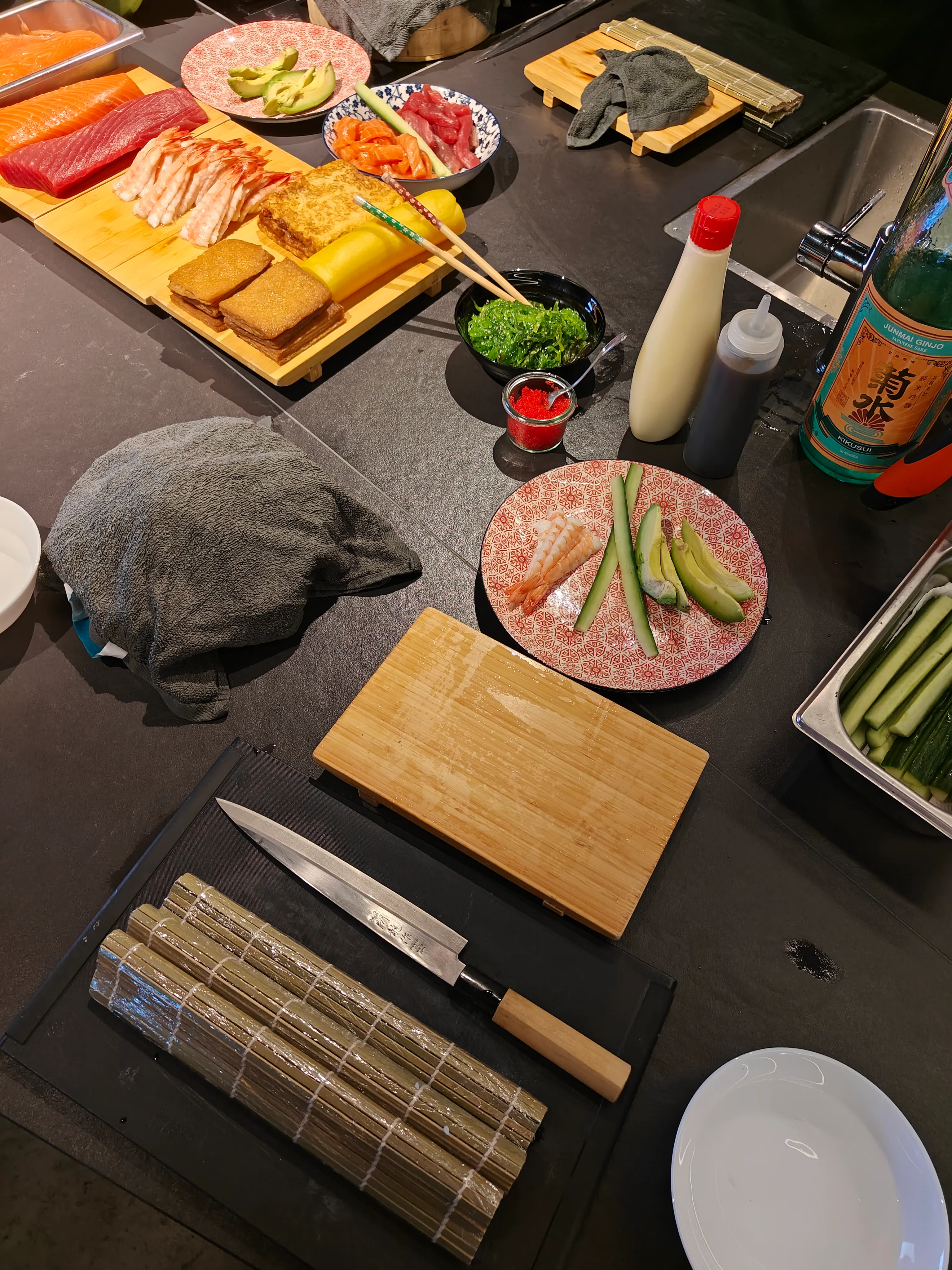 Sushi-Zutaten und Werkzeuge auf Küchentheke.