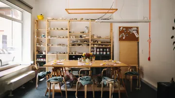 Room with wooden tables and shelves, creative workspace.