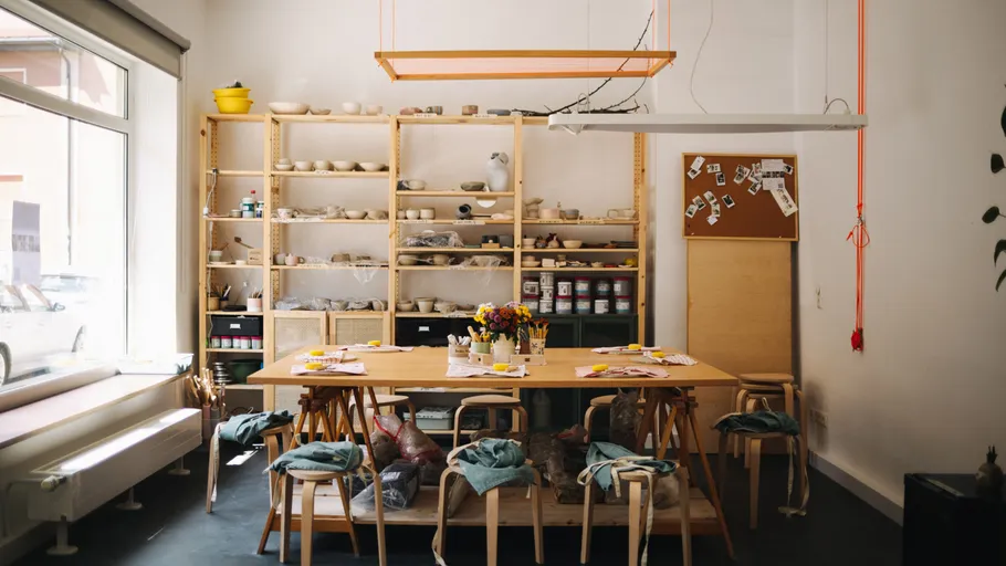 Raum mit Holztischen und Regalen, kreativer Arbeitsbereich.