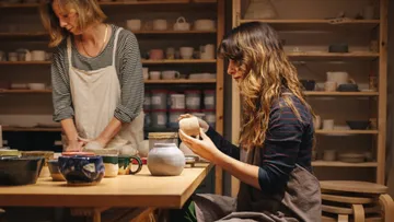 Two women crafting pottery in a studio.