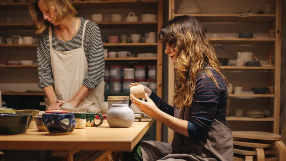 Zwei Frauen töpfern in einem Studio.