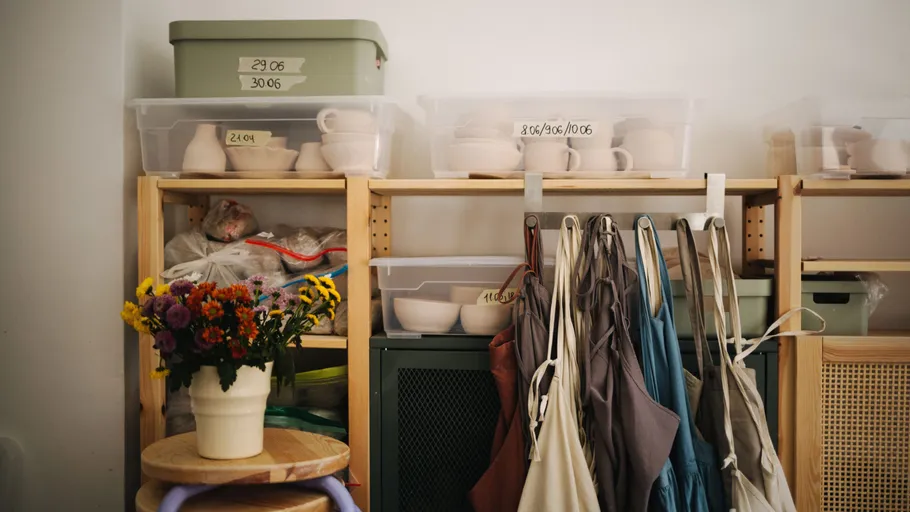 Studio shelves with pottery and hanging aprons.