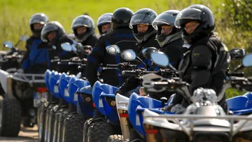 Gruppe von Personen fährt blaue Quads im Freien.