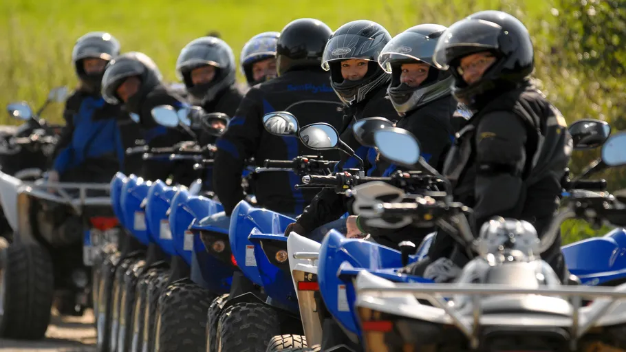 Group of people riding blue quad bikes outdoors.