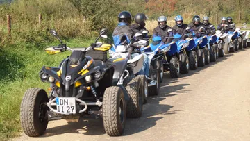 ATVs with riders aligned on dirt road.