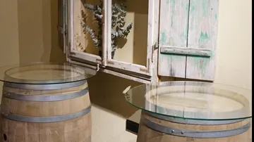 Fass-Tische mit Glasplatten nahe Fenster.