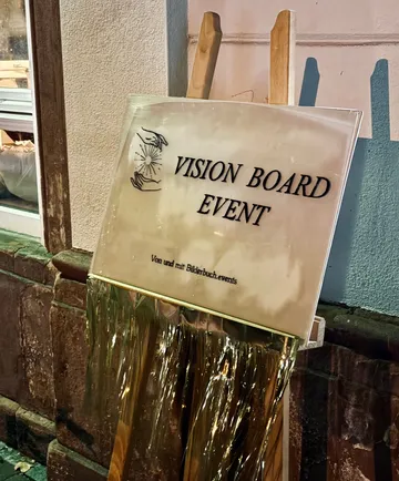 Schild wirbt für Vision Board Event draußen.