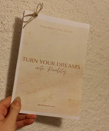 Hand hält Vision Board 2023 Heft.