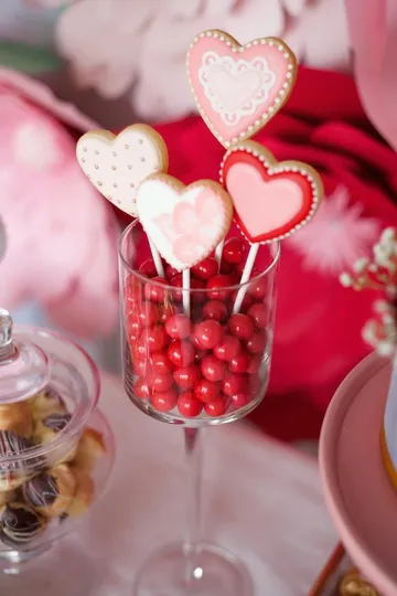 Heart-shaped cookies in glass with red candies.