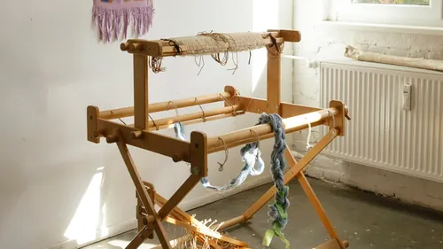 Wooden loom with yarn in bright room.