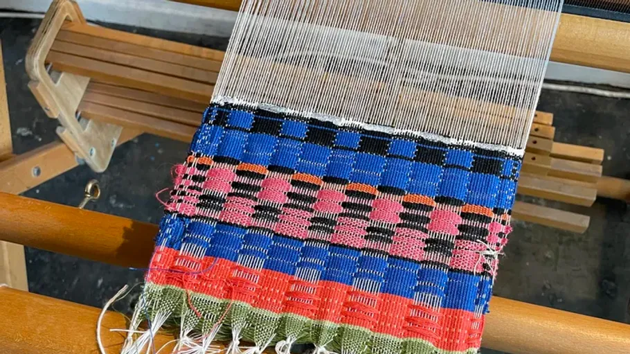 Wooden loom weaving colorful fabric.