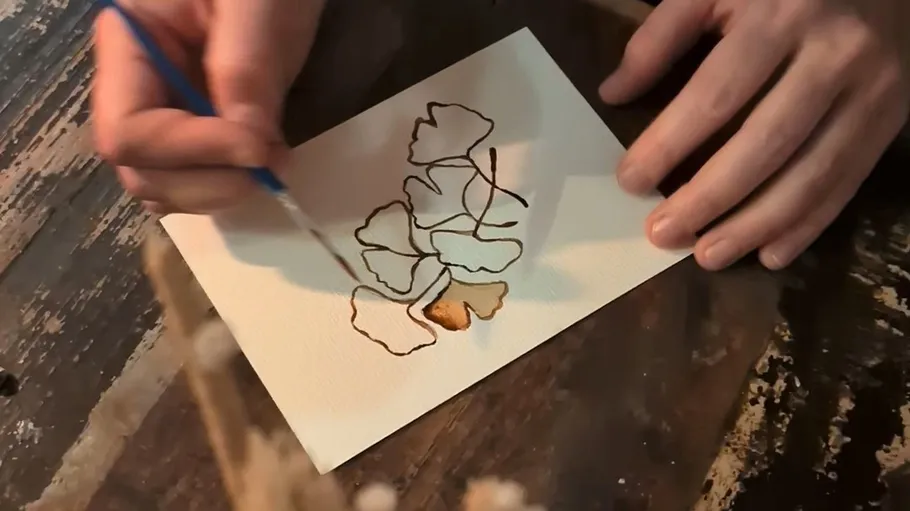Hand painting leaves on paper with brush.
