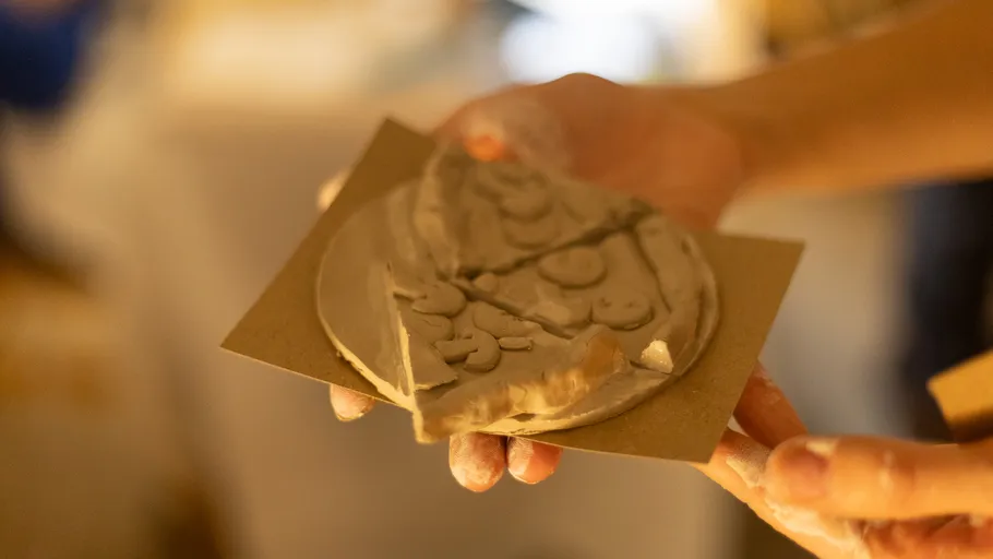 Hands holding a small clay art piece.