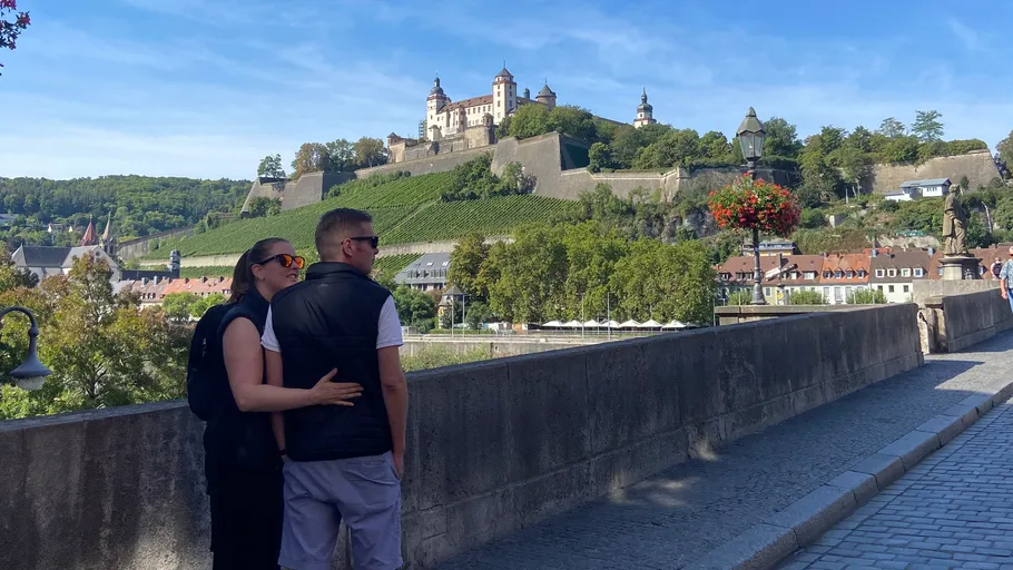 Paar umarmt sich auf Brücke mit Schlossblick.