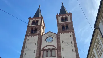 Zwei Kirchtürme mit Uhr unter blauem Himmel.