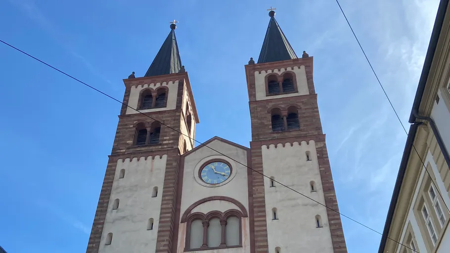 Two church towers with clock under blue sky.