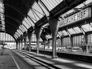 Bahnhof Karlsruhe Hbf mit Gleisen und wartenden Passagieren.