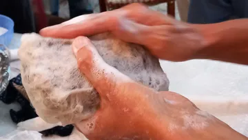 Hände waschen ein Tuch mit Seifenschaum.