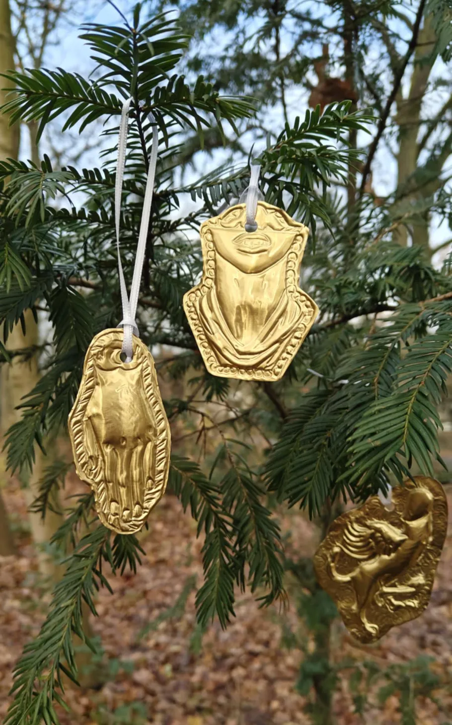 Goldene Anhänger hängen an Baumzweigen.