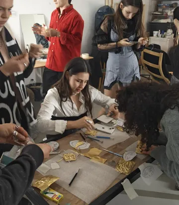 People crafting at a table, using tools.
