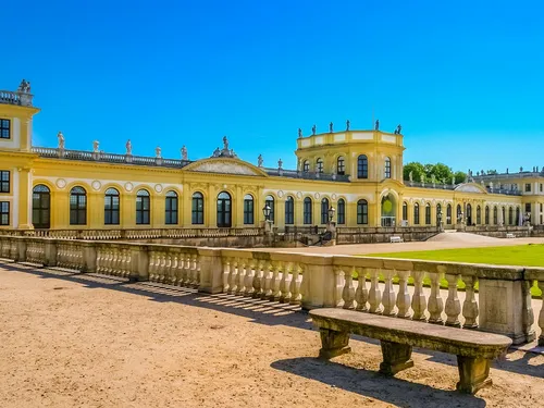 Yellow castle stands against a clear blue sky surrounded by lawn.