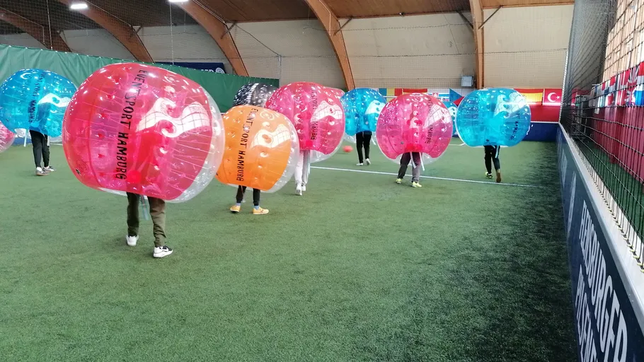 Players wearing bubble suits inside sports hall.