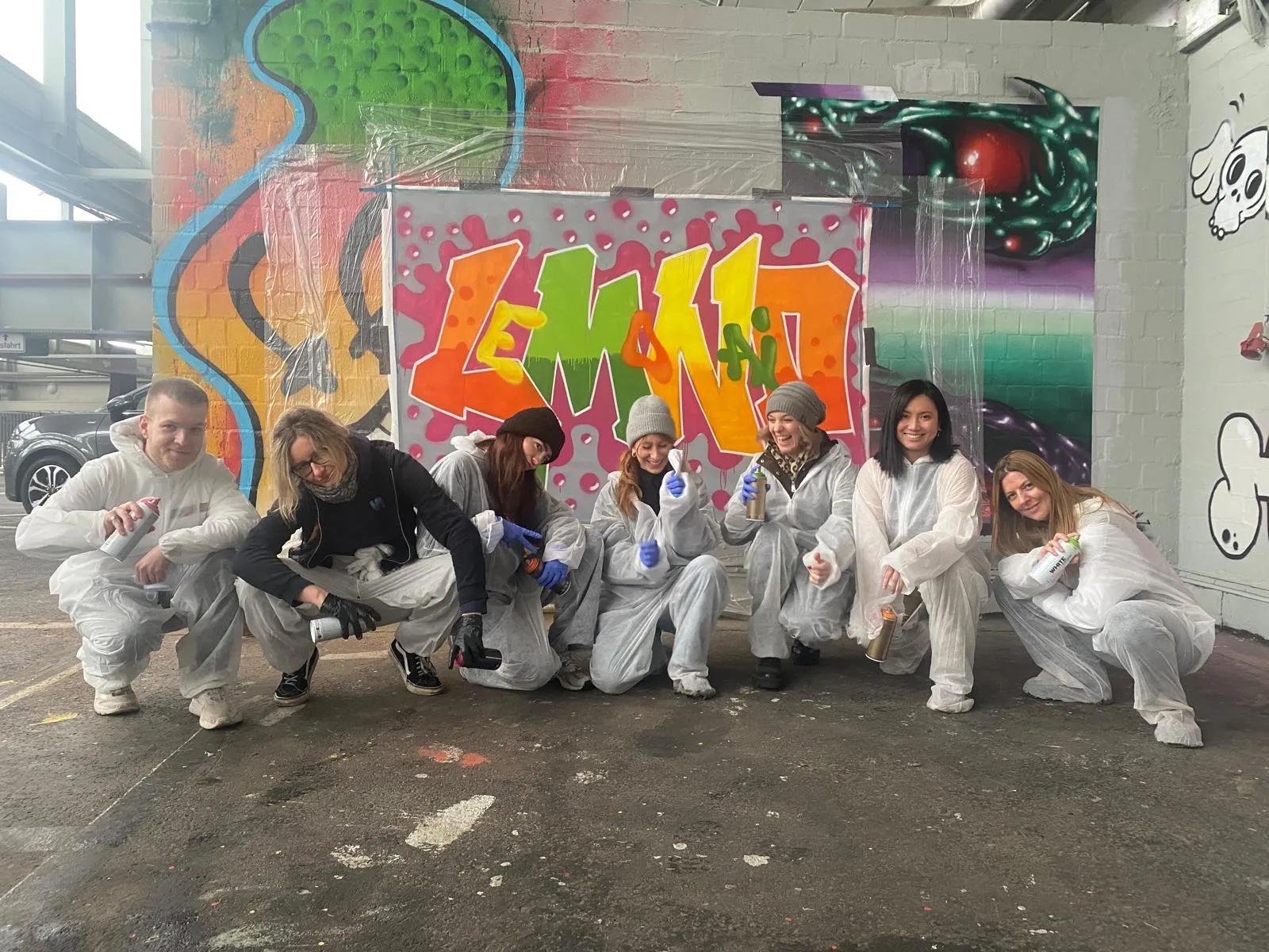 Gruppe posiert vor bunter Graffiti.